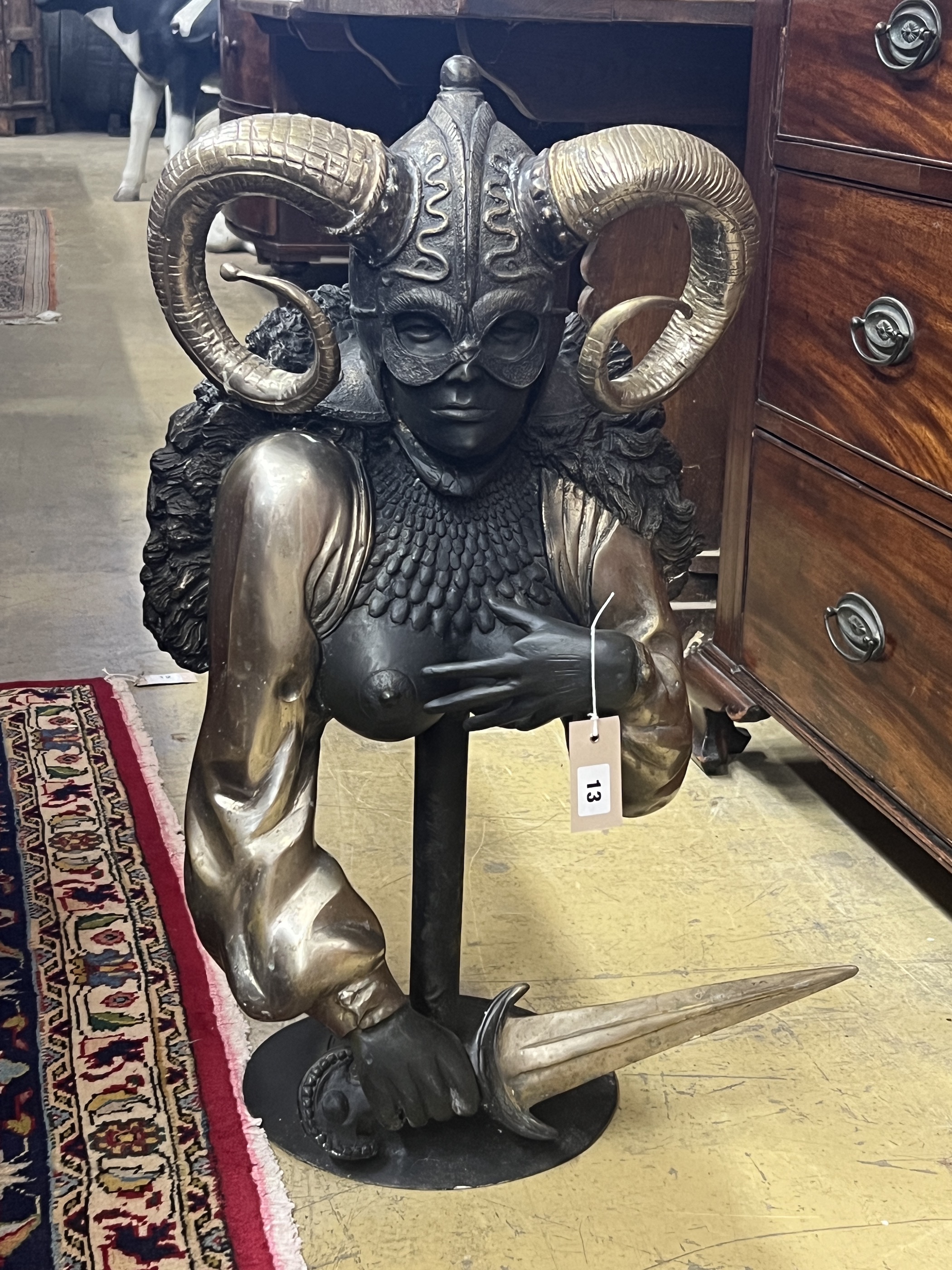 A patinated and polished metal masked female warrior bust on stand, height 70cm